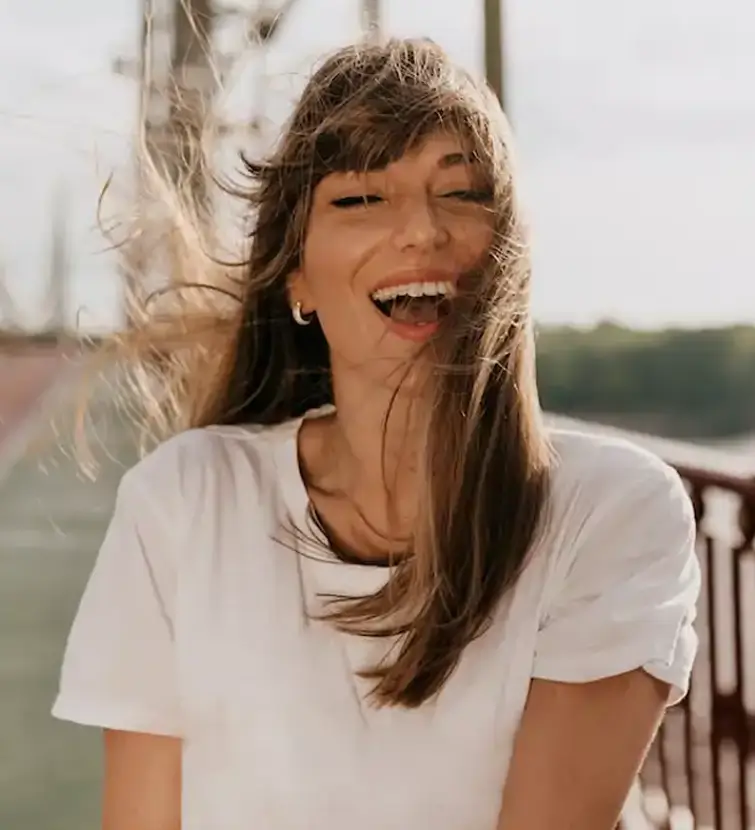Confident woman stands in the wind, laughing as her hair blows around her face