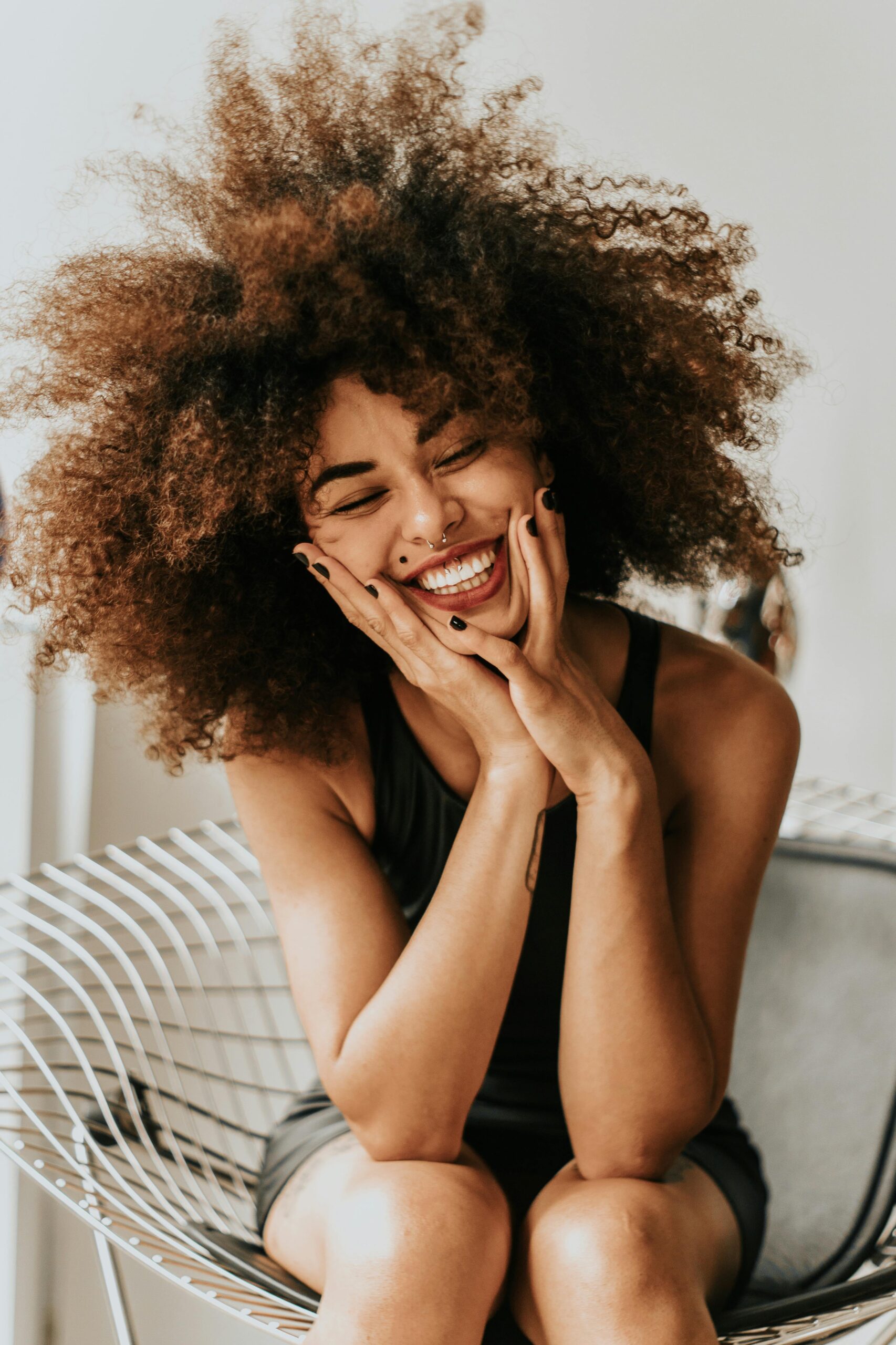 Confident woman stands in the wind, laughing as her hair blows around her face